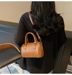 Rear view of model wearing a brown leather Boston bag with gold-tone hardware details