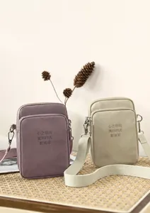Detailed shot of lavender and beige nylon mini crossbody bags on a woven mat background