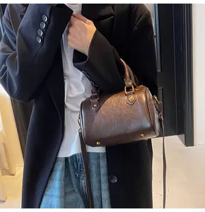 Detalle del bolso Boston marrón vintage con piel brillante y accesorios metálicos dorados