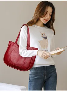 Detail of red leather tote bag with lychee texture and large front pocket on shoulder