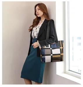 Detail view of large tote bag with geometric patchwork design and black shoulder straps