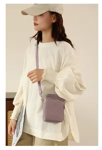 Lifestyle shot of a purple nylon crossbody phone bag styled with a casual outfit