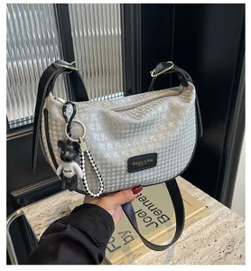 Detail of silver geometric textured dumpling bag with leather strap and bear charm