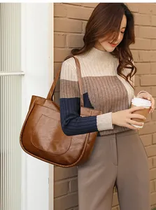 Close-up of a large brown faux leather tote bag with a functional front pocket detail