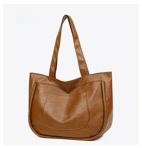Side view of brown leather tote bag showing textured PU material and curved front pocket