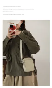 Detail view of a beige nylon crossbody phone bag with double zippers and adjustable wide strap