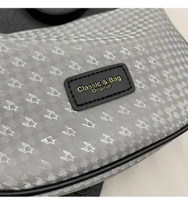 Detail of grey geometric pattern with a black brand leather patch on a crossbody bag