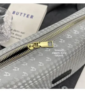 Detailed macro view of the smooth golden metal zipper and star pattern on a gray bag