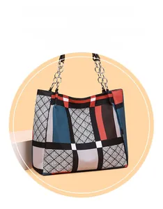 Detail view of colorful geometric patchwork tote bag with silver metal chain straps