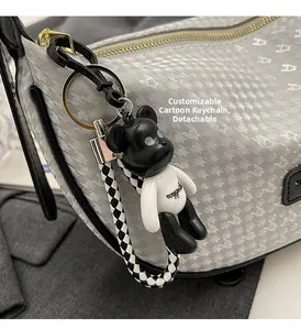 Detail of a cartoon bear keychain with checkered strap on a stylish gray shoulder bag