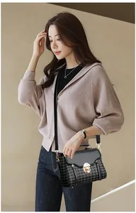 Fashion model styling a black checkered crossbody bag with golden twist lock detail