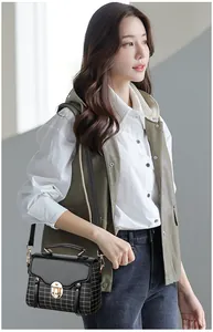 Chic black crossbody bag with white grid pattern and golden clasp shown on a model