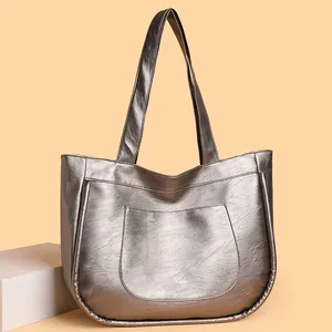 Silver metallic tote bag with wrinkled texture and front pocket on orange background