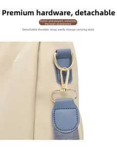 Détail de la bandoulière amovible avec mousqueton doré sur le sac à dos beige