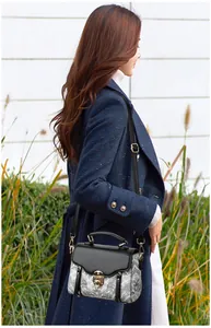 Outdoor shot of a vintage patterned crossbody bag on a navy coat with golden clasp detail