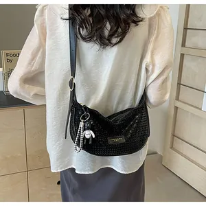 Detail of black textured hobo bag with teddy bear pendant and metallic plaque