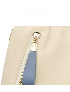 Détail de la fermeture éclair dorée et de la languette en cuir bleu sur le sac à dos