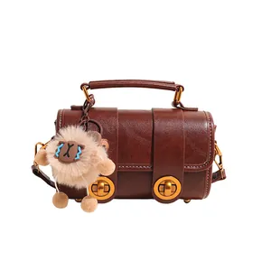 Dunkelbraune Retro Boston Handtasche aus Leder mit Goldteilen und Plüsch-Anhänger