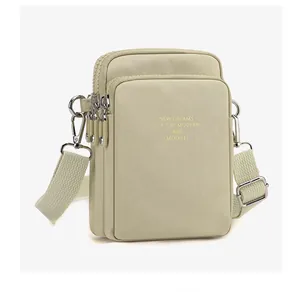 Detailed side view of the triple zipper compartments on the nylon crossbody phone bag