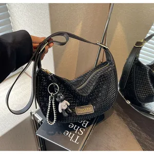 Detail of black crescent hobo bag with star texture, gold zipper and cute bear charm