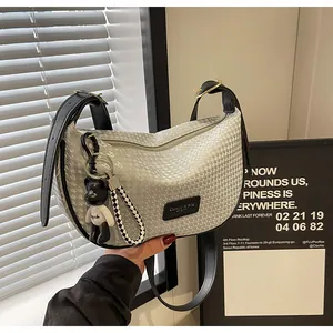 Detailed close-up of silver-grey woven shoulder bag with black strap and bear charm