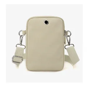 Detail view of beige nylon crossbody bag featuring silver hardware and a headphone jack hole