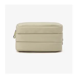 Detail view of the beige nylon cross-body bag with triple-compartment storage and ring zippers