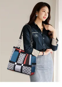 Detail of large nylon plaid tote bag with silver chain strap and leather shoulder handle