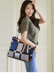 Detail of color-block tote bag featuring geometric patterns and metal chain shoulder strap