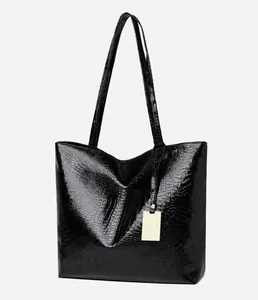 Micro side view of large crocodile pattern tote bag with polished finish and gold tag