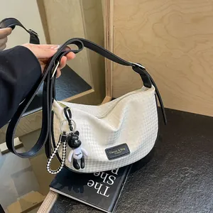 White minimalist Hobo crescent bag with grid texture and black bear charm pendant