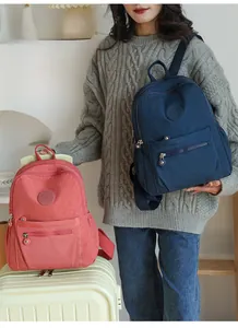 Detail of pink and navy nylon backpacks with front zip pocket and round logo patch