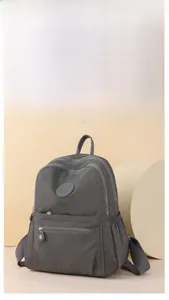 Detail view of water-resistant gray nylon backpack with multiple zipper pockets and logo