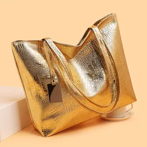 Metallic gold crocodile pattern tote bag with double shoulder straps on warm background