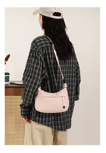 Light pink nylon crescent crossbody bag with adjustable strap and front zipper detail