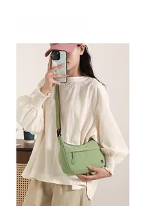 Close-up of a light green crescent crossbody bag with adjustable wide fabric strap