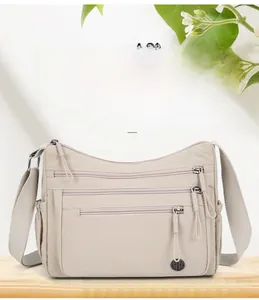 Détails du sac à bandoulière en nylon beige avec poches zippées et logo en métal