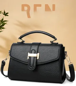 Detail of black pebbled leather texture on tote bag with golden metal ring handles and hardware