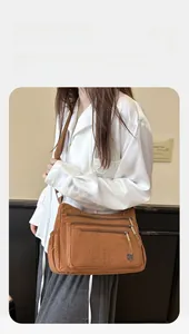 Vue détaillée des compartiments zippés et du nylon imperméable du sac bandoulière
