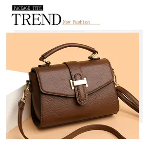 Detail of dark brown leather handbag with gold metal clasp and top handle texture