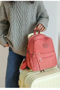 Detail of coral pink nylon backpack mounted on a yellow suitcase handle for travel