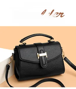 Close-up of black lychee grain leather handbag with gold H-shaped buckle and long strap