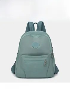 Detailed view of mint green nylon backpack featuring front zipper pocket and round logo