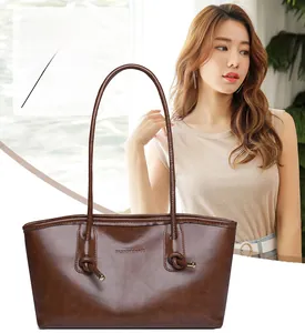 Détail d'un grand sac cabas en cuir marron foncé avec anse nouée et logo de la marque