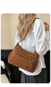 Detail of brown nylon crossbody bag featuring three zippered layers and textured fabric