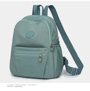 Detail view of a light green nylon backpack with multiple zipper pockets and side slots