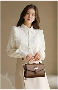 Detail of vintage brown leather handbag with metal buckle worn by model in a city outfit