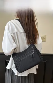 Vue détaillée du sac bandoulière en nylon noir avec poches zippées et logo en métal