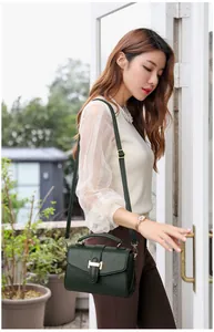 Detail of dark green lychee grain leather handbag with gold H buckle and slim shoulder strap