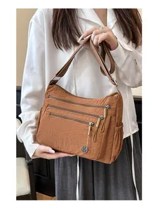 Gros plan d'un sac bandoulière en nylon marron avec plusieurs poches et logo en métal
